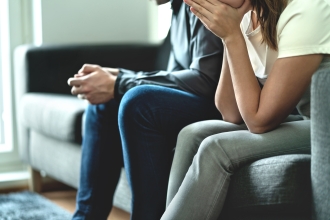 zwei Menschen sitzen auf einem Sofa nebeneinander Gesten der Hände zeigen Konflikt an