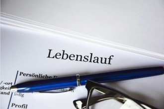 Stift und Brille liegen auf einem Papier mit der Überschrift Lebenslauf