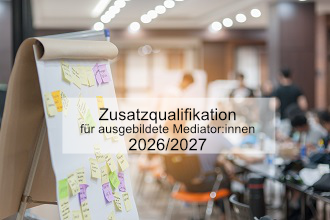 Im Vordergrund: eine Fipchart mit Klebezetteln. Im Hintergrund (unscharf) Menschen sitzen auf Stühlen zusammen. 